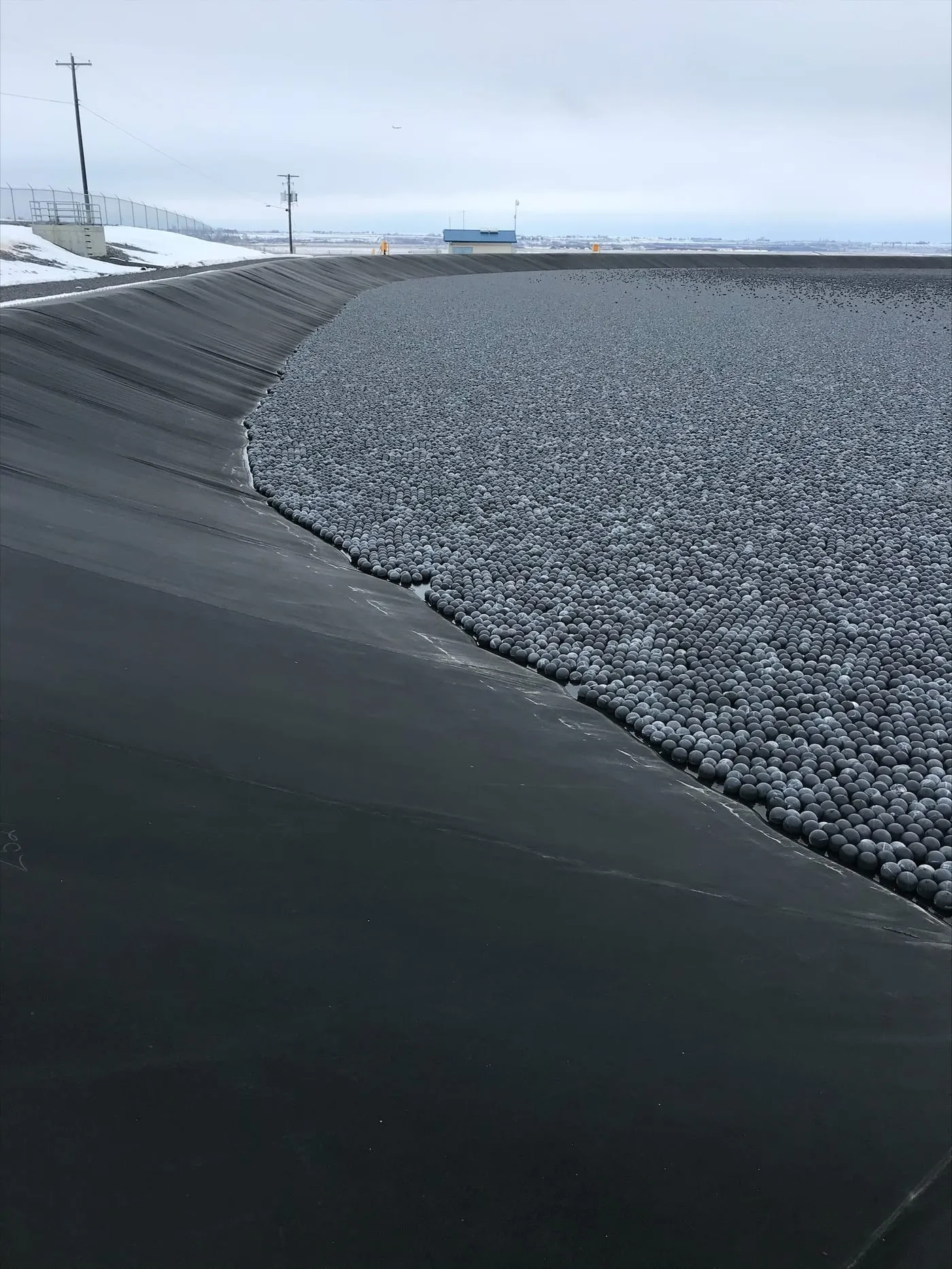 Armor Ball® AQUA water-ballasted covers on a large lined pond in an open, wind-exposed setting.