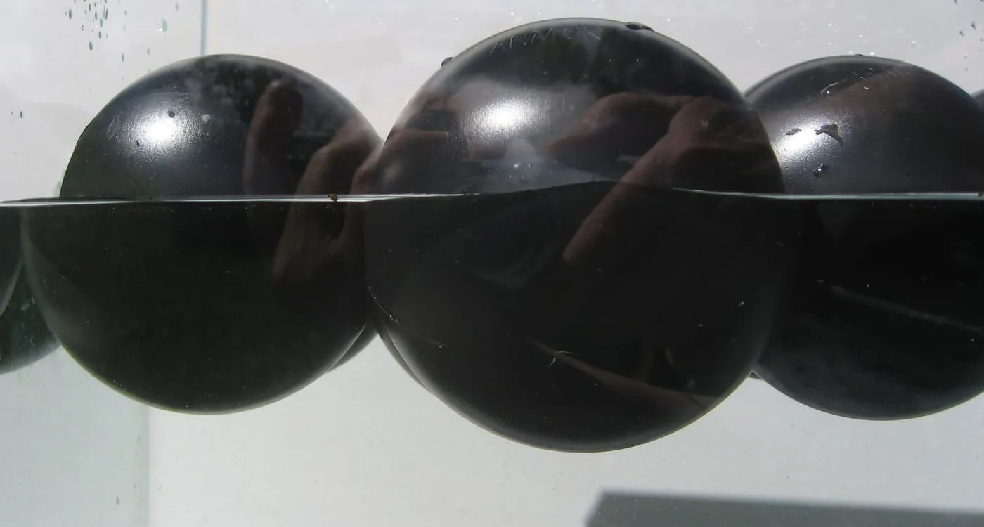 Cross-section view at the waterline showing Armor Ball® covers floating low and self-filled with water ballast.